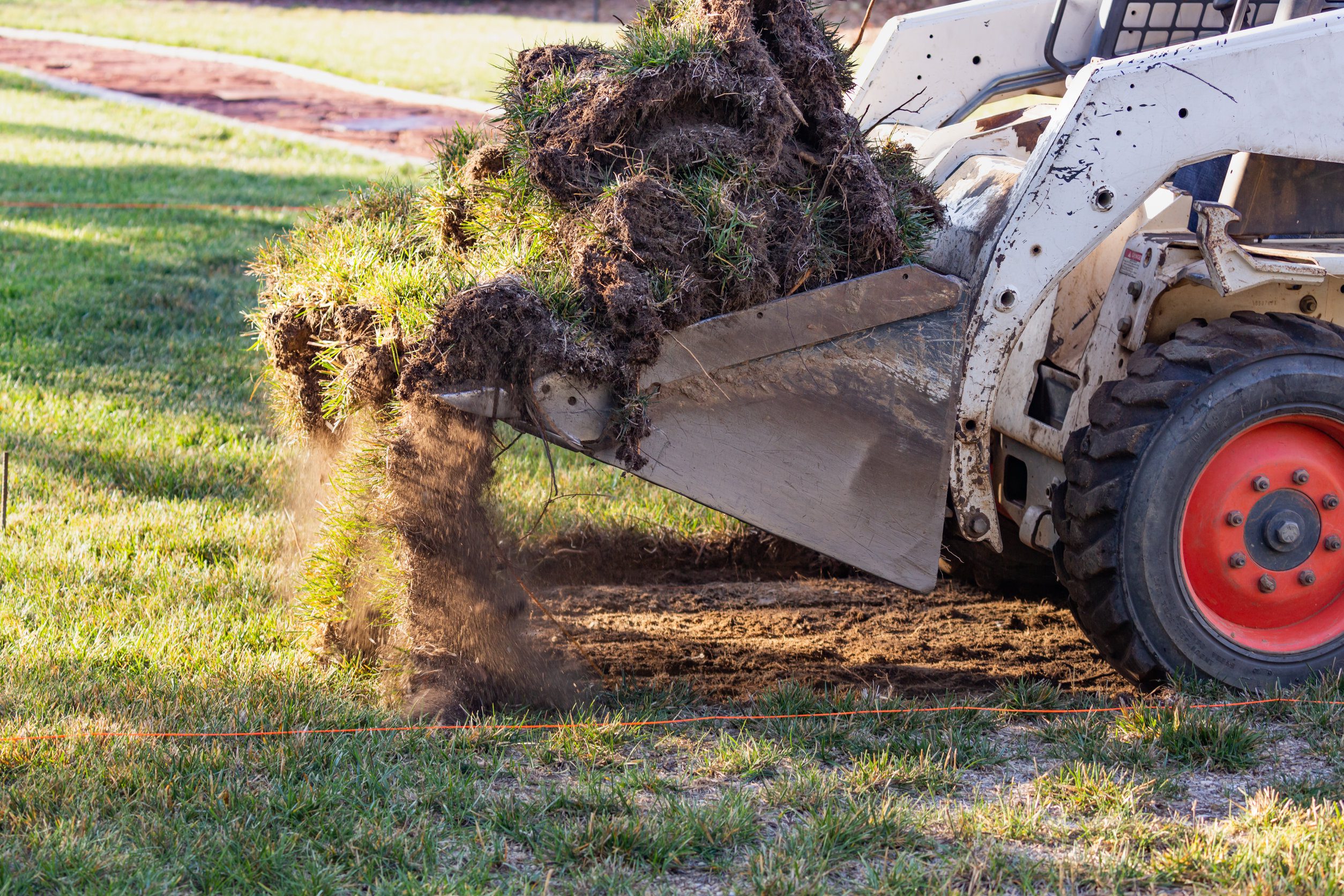 Small Bulldozer Removing Grass From Yard Preparing For Pool Installation